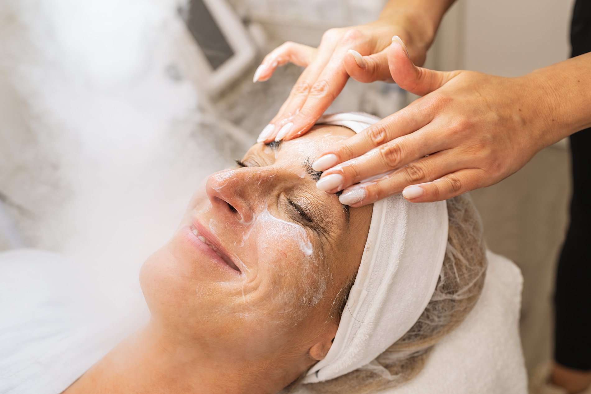 Happy woman has beauty treatment of face with ozone facial steam